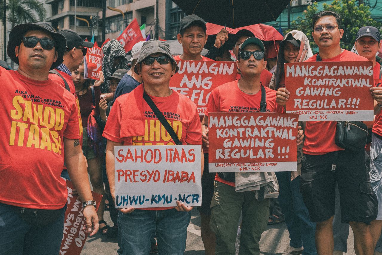 A group of adults protesting for regularization and higher wages in Manila.